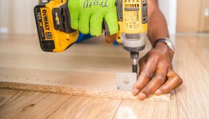 Person Using Dewalt Cordless Impact Driver on Brown Board